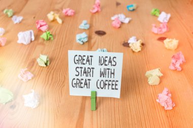 El yazısı harika fikirler harika kahveyle başlar. Kavram, ilham almak için sıcak bir içecek al demek. Renkli, buruşuk kağıtlar boş, ahşap zemin çamaşır mandalı..