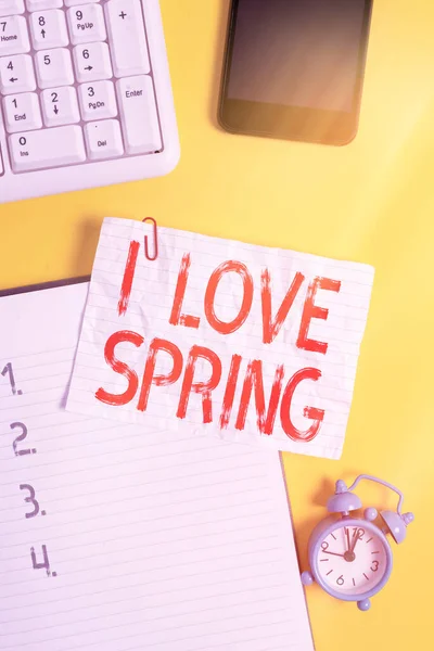 "Baharı Seviyorum" el yazısı. Kavram, bu sezona neden bu kadar düşkün olduğunu açıklıyor. Kağıt raptiyeli beyaz kağıt, mobil saat ve klavye.. — Stok fotoğraf
