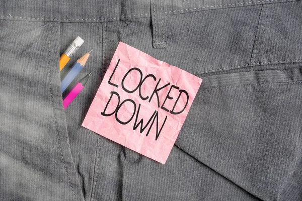 Text sign showing Locked Down. Conceptual photo emergency measure which showing prevented from restricted area Writing equipment and pink note paper inside pocket of man work trousers.