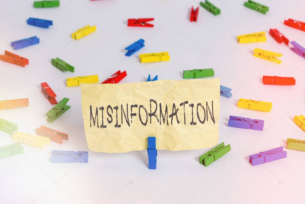 Handwriting text writing Misinformation. Concept meaning false data, in particular, intended intentionally to deceive Colored clothespin papers empty reminder white floor background office.