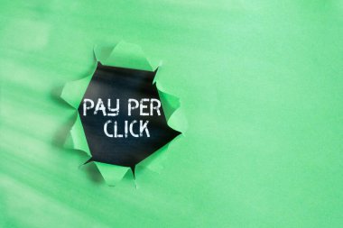 Tıklama başına Ödeme 'yi gösteren not yazıyorum. İş fotoğraflarında internet pazarlaması hangi ödemenin tıklama ile yapıldığını gösteriyor. Klasik ahşap bir masanın üzerinde parçalanmış karton..