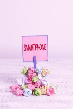 Smartphone 'u gösteren mesaj işareti. Kavramsal fotoğraf. Bilgisayarların çoğunu çalıştıran bir cep telefonu. Hatırlatma öbeği. Renkli buruşuk kağıt çamaşır tokası..