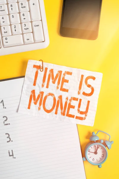 Handschrift tekst schrijven Tijd Is Geld. Concept betekent om dingen zo snel mogelijk te doen en geen tijd te verspillen Verfrommeld wit papier op tafel met paperclips klok mobiel en pc-toetsenbord. — Stockfoto