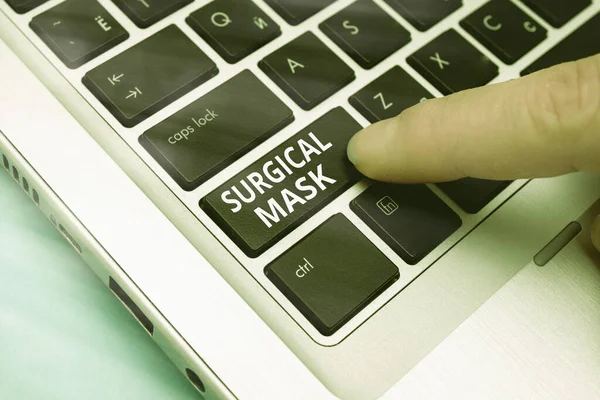 Word writing text Surgical Mask. Business concept for worn by health professionals during surgery and during nursing Pc keyboard key with pointing finger above background copy space.