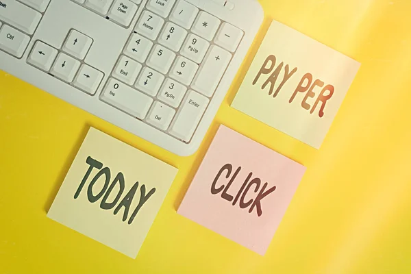 Handwriting text Pay Per Click. Concept meaning internet marketing in which payment is based on clickthrough Colored empty papers with copy space on the yellow background table with pc keyboard.