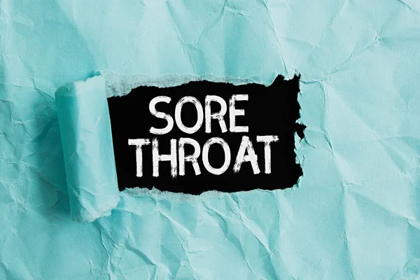 Handwriting text Sore Throat. Concept meaning Inflammation ot the pharynx and fauces resulted from an irritation Rolled ripped torn cardboard placed above a wooden classic table backdrop.