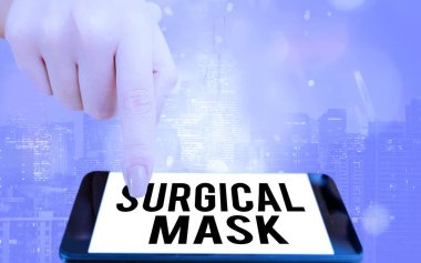 Cerrahi Maske 'yi gösteren bir not yazıyorum. Sağlık uzmanları tarafından ameliyat sırasında giyilen iş fotoğrafı sergisi ve renkli bokeh arka plan altında modern cihazlar beyaz ekranda gösteriliyor..