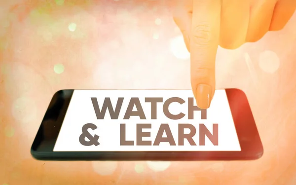 Υπογραφή κειμένου που δείχνει το Watch And Learn. Εννοιολογική φωτογραφία που δείχνει μια δράση ή ιδέες για το πώς να κάνει τα πράγματα Σύγχρονα gadgets με λευκή οθόνη προβολής κάτω από πολύχρωμο φόντο bokeh. — Φωτογραφία Αρχείου