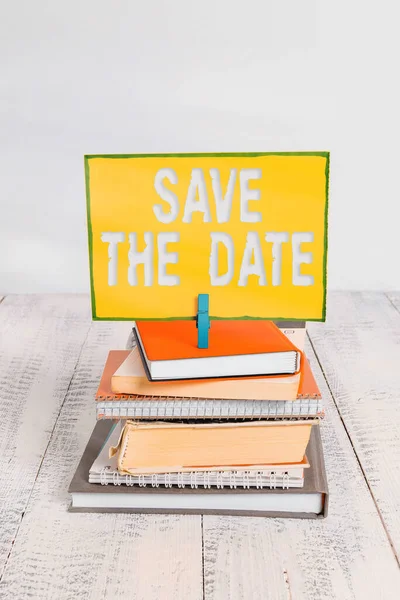 Handwriting text Save The Date. Concept meaning Organizing events well make day special event organizers pile stacked books notebook pin clothespin colored reminder white wooden. — Stock Photo, Image