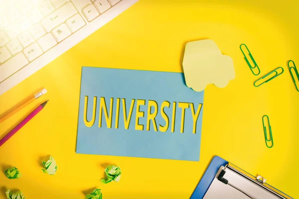 Text sign showing University. Conceptual photo an educational institution designed to teach and investigate Flat lay above empty paper with copy space and colored paper clips. — Stock Photo, Image