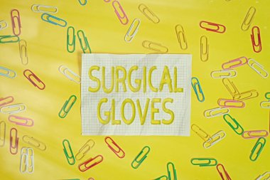 Sözcük yazma metni Cerrahi Eldiven. Bulaşıcı materyallere maruz kalmaktan korunmak için iş konsepti fotokopi alanı ve renkli ataçlarla boş kağıdın üzerinde yatıyordu.
