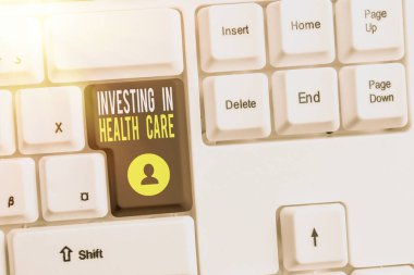 Sağlık hizmetlerine yatırım yapıldığını gösteren kavramsal el yazısı. İş fotoğraflarının sergilenmesi, sağlık bakımına veya iyileştirmeye para yatırdı. Fotokopi alanına aksesuarları yerleştirilmiş renkli klavye anahtarı.