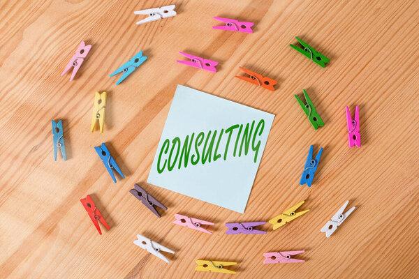 Writing note showing Consulting. Business photo showcasing business of giving expert advice typically in business matters Colored clothespin papers empty reminder wooden floor background office.