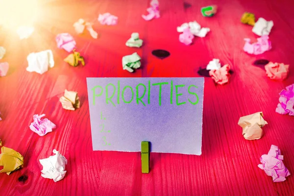 Writing note showing Priorities. Business photo showcasing fact or condition of being regarded or treated as more important Colored crumpled rectangle shaped reminder paper light blue background. — Stock Photo, Image