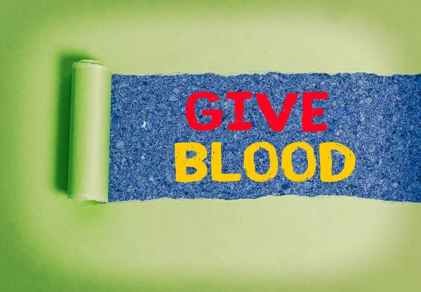 Texto de escritura Donar Sangre. Concepto que significa que un individuo voluntariamente tiene sangre extraída y utilizada para transfusiones. Cartón desgarrado laminado colocado sobre un fondo de mesa clásico de madera. . — Foto de Stock