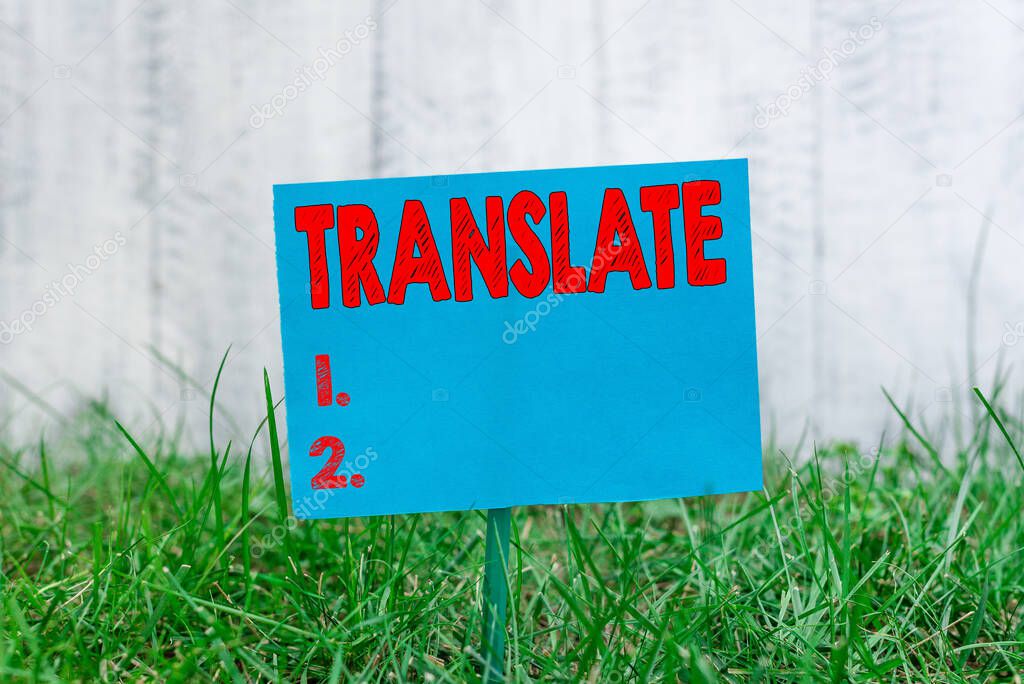 Handwriting text Translate. Concept meaning bear, remove, or change from one place, state, form, or appearance Plain empty paper attached to a stick and placed in the green grassy land.