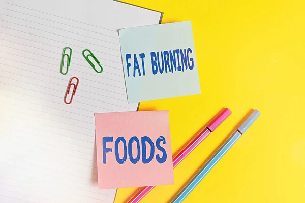 Handstil text Fett Burning Foods. Begreppet innebär att producera fettförbränning genom att stimulera ämnesomsättningen för att minska aptiten Tomt blått papper med kopia utrymme gem och pennor på det gula bordet. — Stockfoto