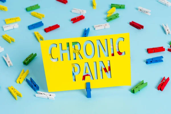 Text sign showing Chronic Pain. Conceptual photo discomfort that persists or progresses over a long period Colored clothespin papers empty reminder blue floor background office pin.
