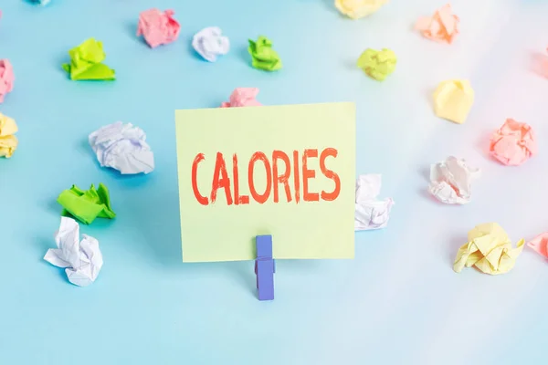 Texte d'écriture de mots Calories. Concept d'entreprise pour une quantité d'aliments ayant une valeur de l'énergie d'une grande calorie Papiers froissés colorés rappel vide fond bleu pince à linge. — Photo