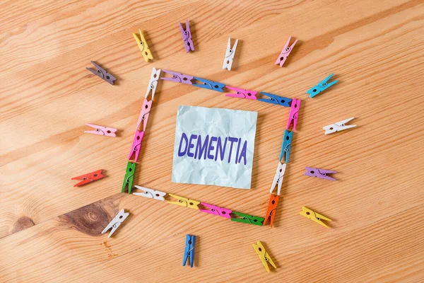 Handwriting text Dementia. Concept meaning usually, a progressive condition marked by multiple deficits Colored clothespin papers empty reminder wooden floor background office. — Stock Photo, Image