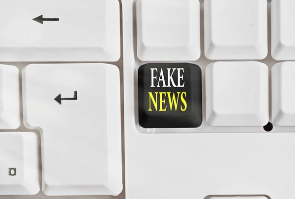 Conceptual hand writing showing Fake News. Business photo showcasing false information publish under the guise of being authentic news Colored keyboard key with accessories arranged on copy space.