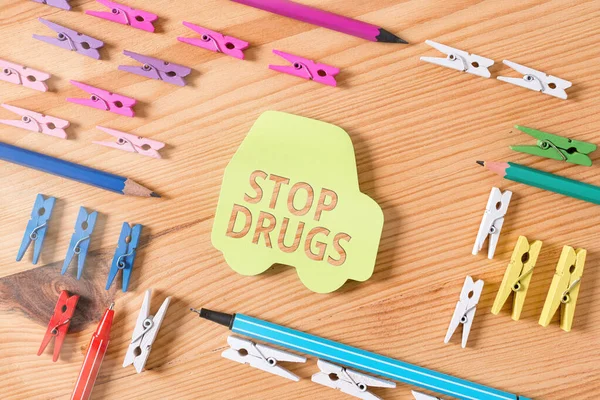 Texto escrito por palavra Stop Drugs. Conceito de negócio para acabar com a dependência de substâncias como a heroína ou a cocaína Papéis de roupa coloridos lembrete vazio piso de madeira de fundo escritório . — Fotografia de Stock