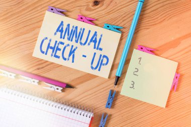 Yıllık kontrolleri gösteren kavramsal el yazısı. Bir sağlık hizmeti sağlayıcısıyla yıllık üreme sağlığı ziyareti. Kırışmış kağıtlar. Ahşap zemin mandalı..