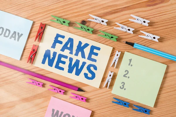 Word writing text Fake News. Geschäftskonzept für Falschinformationen veröffentlichen unter dem Deckmantel der Authentizität Nachrichten Farbige Wäscheklammern Papiere leere Erinnerung Holzboden Hintergrundbüro. — Stockfoto