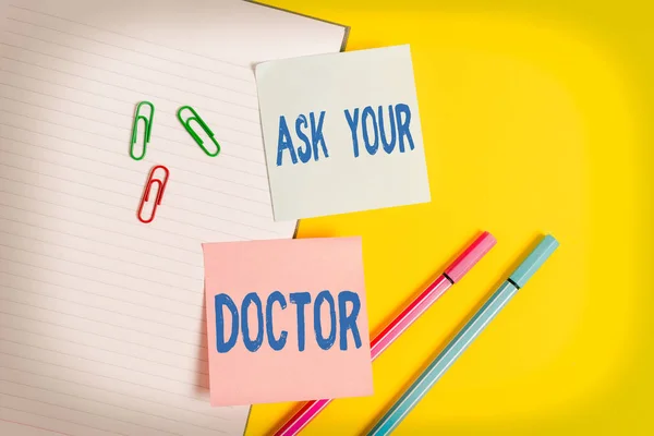 Handschrift tekst Vraag het uw arts. Concept betekent informatie of advies inwinnen bij een arts Leeg blauw papier met kopieerruimte paperclips en potloden op de gele tafel. — Stockfoto