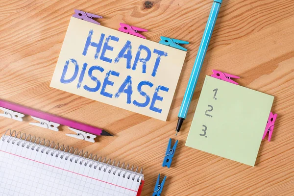 Conceptual hand writing showing Heart Disease. Business photo showcasing A type of disease that affects the heart or blood vessels Colored crumpled papers wooden floor background clothespin. — Stock Photo, Image