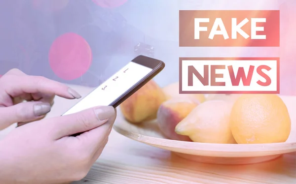 Handwriting text Fake News. Concept meaning false information publish under the guise of being authentic news Modern gadgets with white display screen under colorful bokeh background.