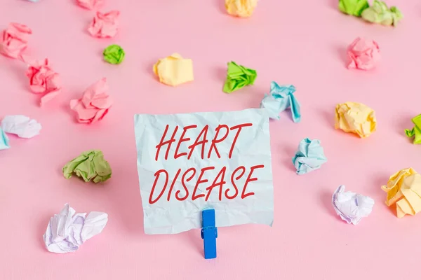 Writing note showing Heart Disease. Business photo showcasing A type of disease that affects the heart or blood vessels Colored crumpled papers empty reminder pink floor background clothespin. — Stock Photo, Image