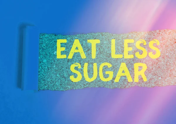 Schrijfbriefje met Eet Minder Suiker. Zakelijke foto presentatie verminderen suiker inname en het eten van een gezond dieet rijk voedsel Gewalst gescheurd karton boven een houten klassieke tafel. — Stockfoto