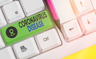 Coronavirus Hastalığı 'nın el yazısı. Anlamı, yeni bir virüs olan SARSCoV2 'nin neden olduğu hastalık olarak tanımlanır. Boş kopyalama alanına aksesuarları yerleştirilmiş farklı renkli klavye anahtarı..