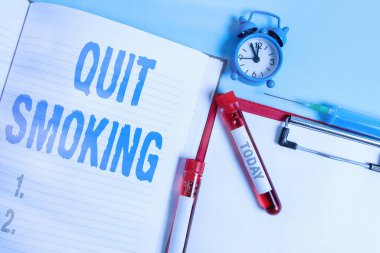 Sigarayı bıraktığını gösteren bir not yazıyorum. Tütün içmeyi durdurma ya da tütün içmeyi durdurma sürecini gösteren iş fotoğrafı. Kan örneği tüpü tıbbi aksesuarları incelenmeye hazır..