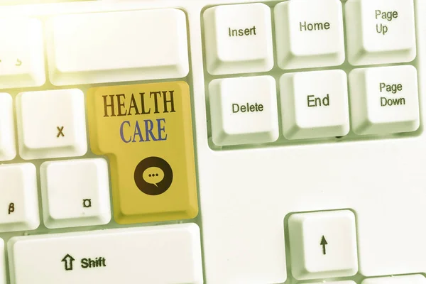 显示医疗保健的书面说明。商业照片展示有组织地向个人或社区提供医疗服务彩色键盘键，其附件放在空白的复制空间上. — 图库照片