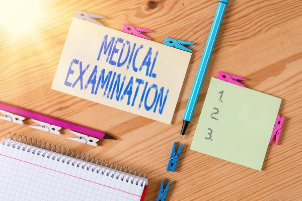 Conceptual hand writing showing Medical Examination. Business photo showcasing the examination carried out to determine physical fitness Colored crumpled papers wooden floor background clothespin.