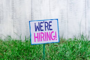 Yeniden işe aldığımız el yazısı metni. Uygulamaları gözden geçirme ve adayları bulma süreci kavramını kavrayarak bir çubuğa bağlı boş kağıt ve yeşil çimenli topraklara yerleştirildi.