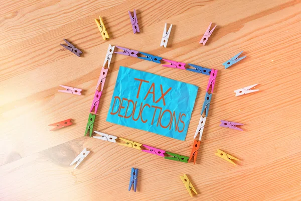 Conceptual hand writing showing Tax Deductions. Business photo text an amount or cost that subtracted from someone s is income Colored crumpled papers wooden floor background clothespin.