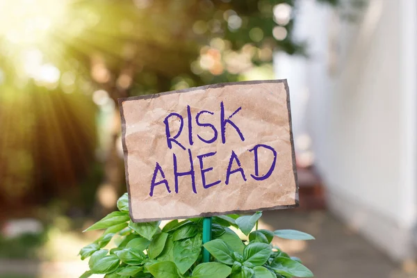 Writing note showing Risk Ahead. Business photo showcasing A probability or threat of damage, injury, liability, loss Plain paper attached to stick and placed in the grassy land. — Stock Photo, Image