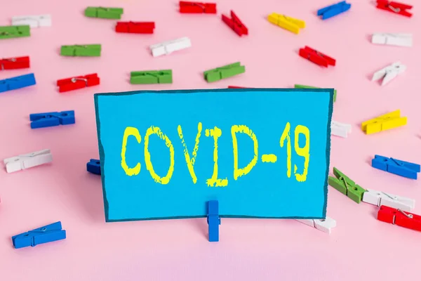 Text sign showing Covid19. Conceptual photo mild to severe respiratory illness that is caused by a coronavirus Colored clothespin papers empty reminder pink floor background office pin. — Stock Photo, Image