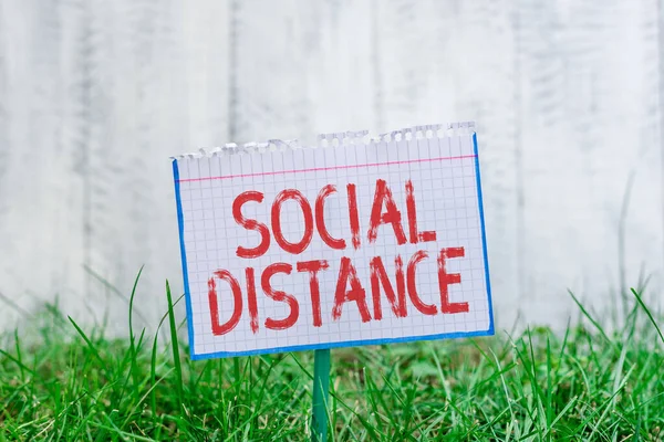 Wortschreibtext Social Distance. Geschäftskonzept für den Grad der Akzeptanz der allgemeinen Interaktion von Individuen Mathematisches Papier an einem Stock befestigt und in der grünen Wiese platziert. — Stockfoto