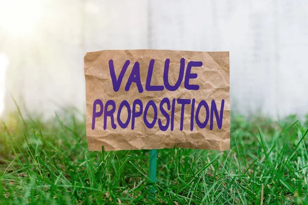 Word writing text Value Proposition. Business concept for feature intended to make a company or product attractive Crumpled paper attached to a stick and placed in the green grassy land. — Stock Photo, Image