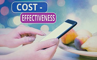 Conceptual hand writing showing Cost Effectiveness. Business photo showcasing degree to which something is effective in relation to its cost. Modern gadgets white screen under colorful bokeh clipart