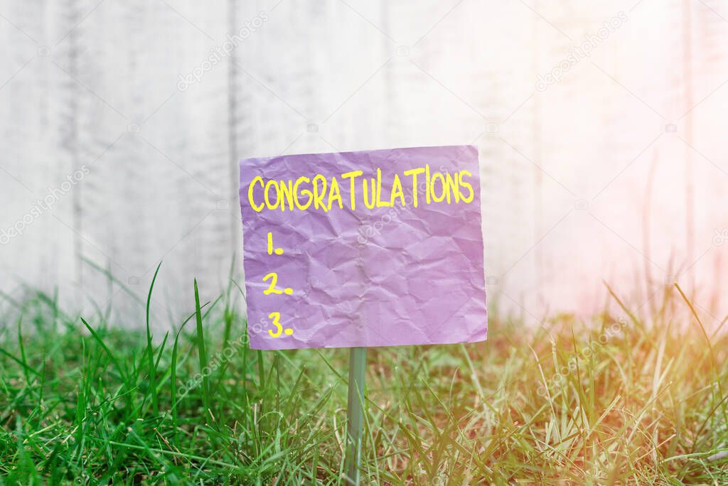 Conceptual hand writing showing Congratulations. Business photo text a congratulatory expression usually used in plural form Plain paper attached to stick and placed in the grassy land.