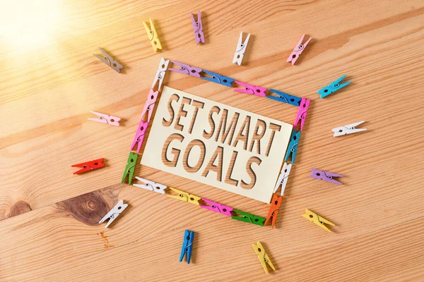 Kelime yazma metni Akıllı Hedefler Belirle. Renkli çamaşır iğnesi kağıtları boş hatırlatıcı ahşap zemin ofis ayarlarında rehberlik edecek kriterler vermek için iş konsepti.