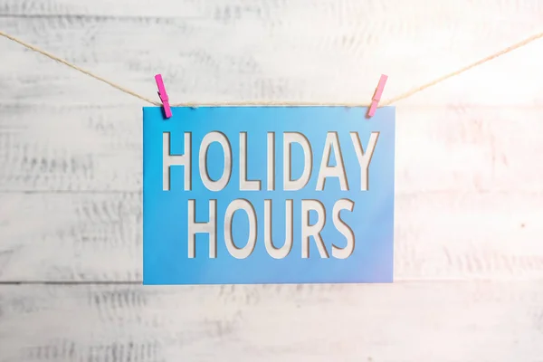 El yazısı, Holiday Hours. Konsept, çalışanın her saat için normal maaşının iki katını alacağı anlamına gelir. Çamaşır ipi, mandal şekilli kağıt, hatırlatıcı beyaz ahşap masa.. — Stok fotoğraf