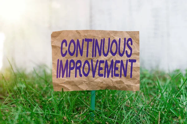 Word writing text Continuous Improvement. Business concept for ongoing effort to improve products or processes Crumpled paper attached to a stick and placed in the green grassy land.
