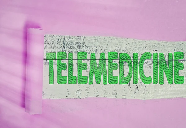 Textzeichen für Telemedizin. Konzeptionelle Fotopraxis Medizin, wenn Untersuchung und Patient getrennt werden Gerollte zerrissene Pappe vor einer klassischen Tischkulisse aus Holz platziert. — Stockfoto