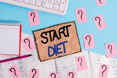 Başlangıç Diyetini gösteren not yazılıyor. Düzenli ve denetimli bir şekilde yemek yeme uygulamasını gösteren bir iş fotoğrafı. Yazma araçları ve ahşap masanın üstüne karalanmış kağıt..